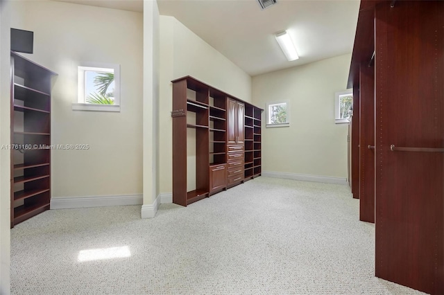 corridor with light colored carpet, visible vents, a healthy amount of sunlight, and baseboards