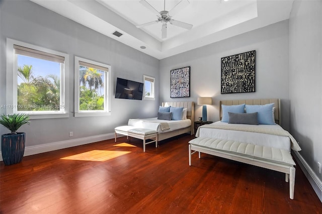 bedroom with baseboards, a raised ceiling, visible vents, and wood finished floors