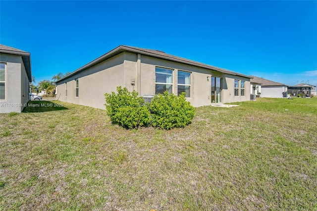 back of property with a lawn and stucco siding