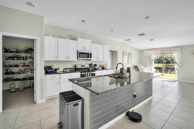 kitchen featuring light tile patterned floors, white cabinets, appliances with stainless steel finishes, and a sink