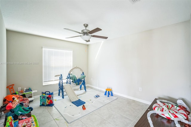 recreation room with tile patterned floors, ceiling fan, and baseboards