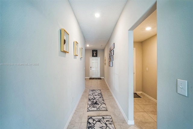 hall featuring light tile patterned floors and baseboards