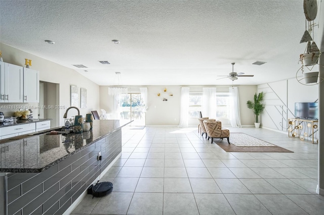 kitchen with a sink, a healthy amount of sunlight, white cabinets, and light tile patterned floors