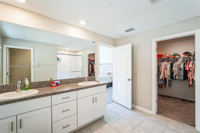 full bath with a shower stall, double vanity, visible vents, and a sink