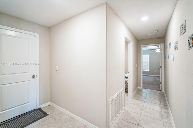 hallway featuring light tile patterned floors, visible vents, and baseboards