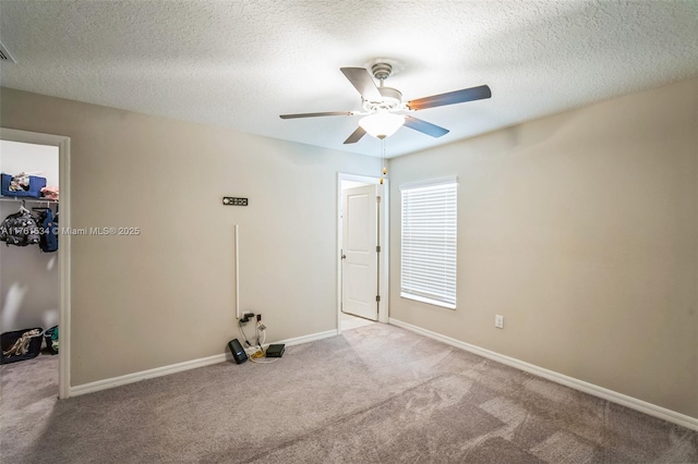 unfurnished bedroom with a walk in closet, baseboards, carpet, a closet, and a textured ceiling