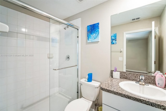 full bathroom with visible vents, a shower stall, toilet, and vanity