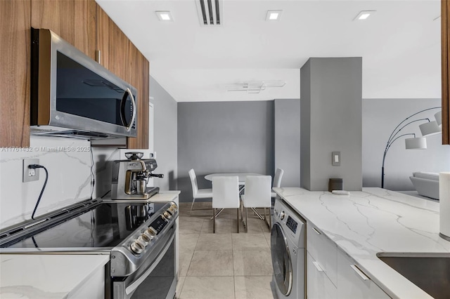 kitchen featuring visible vents, washer / clothes dryer, stainless steel appliances, modern cabinets, and brown cabinets