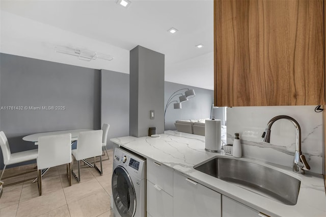 laundry room featuring light tile patterned floors, laundry area, washer / clothes dryer, and a sink