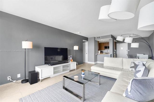 living room with light tile patterned floors, visible vents, and baseboards