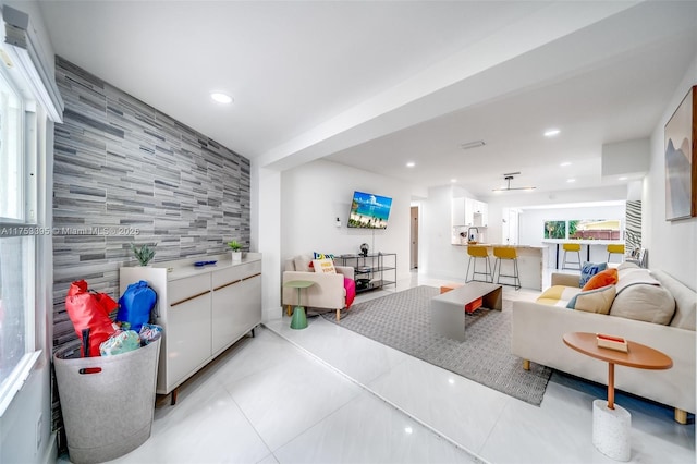 living room featuring light tile patterned floors, tile walls, recessed lighting, and an accent wall