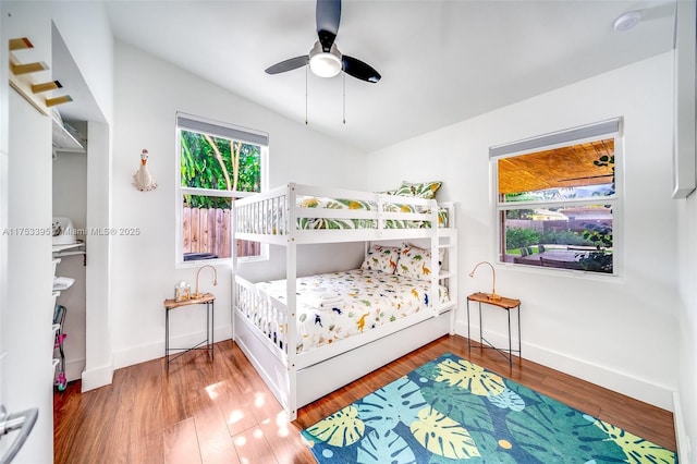 bedroom with ceiling fan, baseboards, wood finished floors, and vaulted ceiling