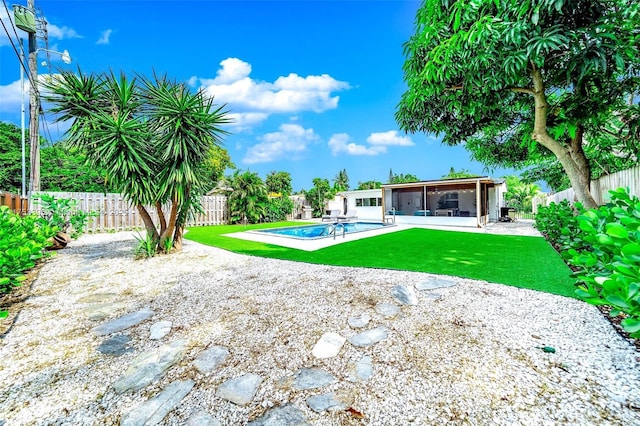 back of property featuring a yard, a fenced in pool, a fenced backyard, and a sunroom