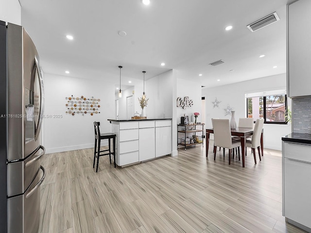 kitchen featuring dark countertops, stainless steel fridge with ice dispenser, and visible vents