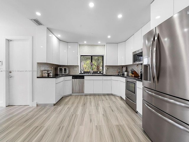 kitchen featuring dark countertops, white cabinets, stainless steel appliances, and modern cabinets