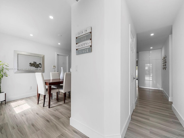 hallway featuring light wood-style flooring, recessed lighting, and baseboards