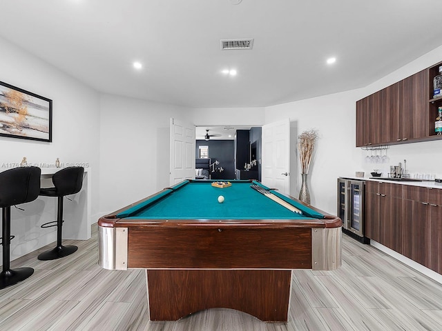 rec room with light wood finished floors, visible vents, wine cooler, indoor wet bar, and a sink