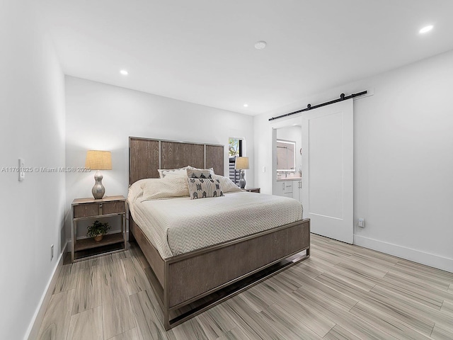 bedroom featuring a barn door, light wood-style flooring, recessed lighting, and baseboards