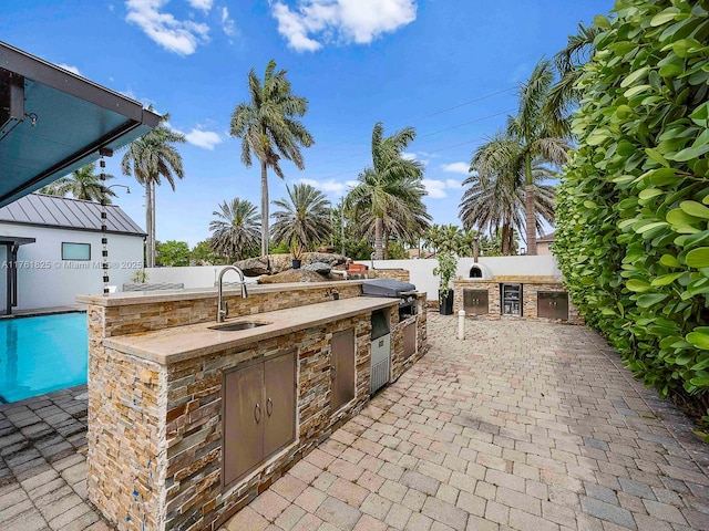 view of patio with an outdoor kitchen, area for grilling, fence, and a sink