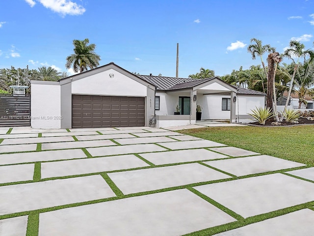 view of front facade with driveway, a standing seam roof, an attached garage, stucco siding, and metal roof