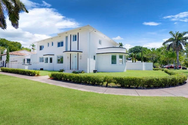 view of front of home with stucco siding, fence, and a front lawn