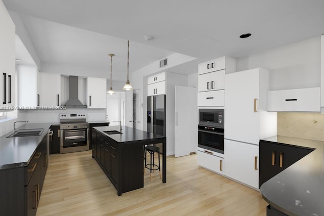 kitchen with wall chimney range hood, a sink, dark cabinetry, and appliances with stainless steel finishes