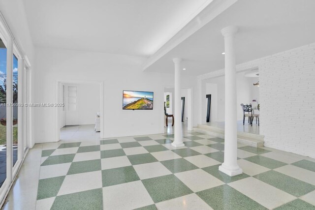 empty room with tile patterned floors, ornate columns, and brick wall