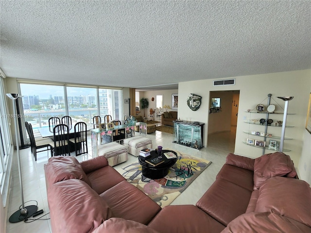 living area featuring tile patterned flooring, floor to ceiling windows, visible vents, and a textured ceiling