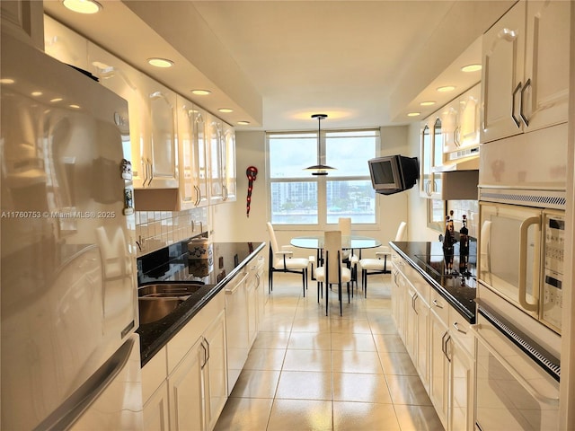 kitchen featuring oven, tasteful backsplash, freestanding refrigerator, dishwashing machine, and black electric stovetop