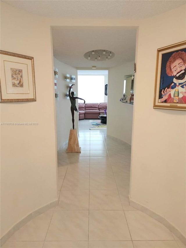 hallway with light tile patterned flooring and baseboards