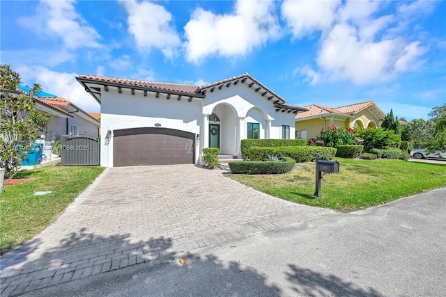 mediterranean / spanish-style home with a front yard, a gate, a garage, a tile roof, and decorative driveway