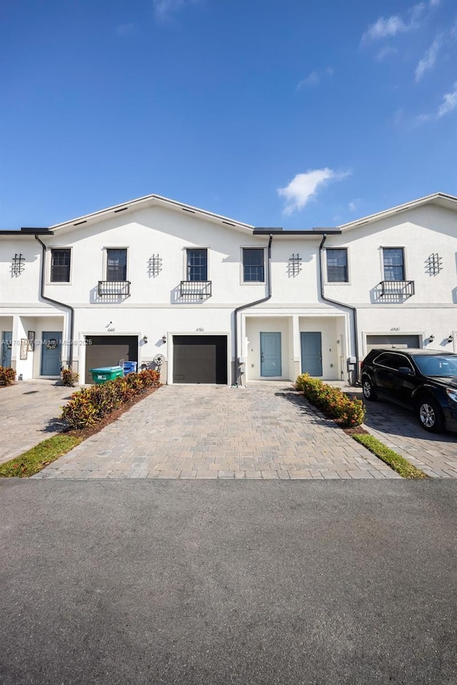 view of property with stucco siding, driveway, and an attached garage