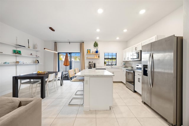 kitchen with a breakfast bar area, light tile patterned floors, appliances with stainless steel finishes, white cabinetry, and open shelves