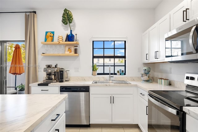 kitchen with a sink, a wealth of natural light, appliances with stainless steel finishes, and white cabinets