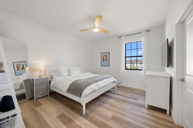 bedroom with light wood finished floors, baseboards, and ceiling fan