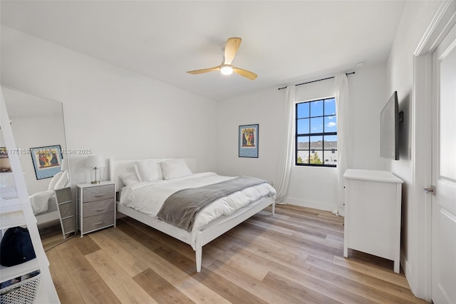 bedroom featuring a ceiling fan, light wood-style floors, and baseboards