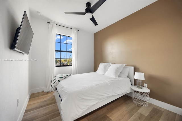 bedroom with ceiling fan, baseboards, and wood finished floors