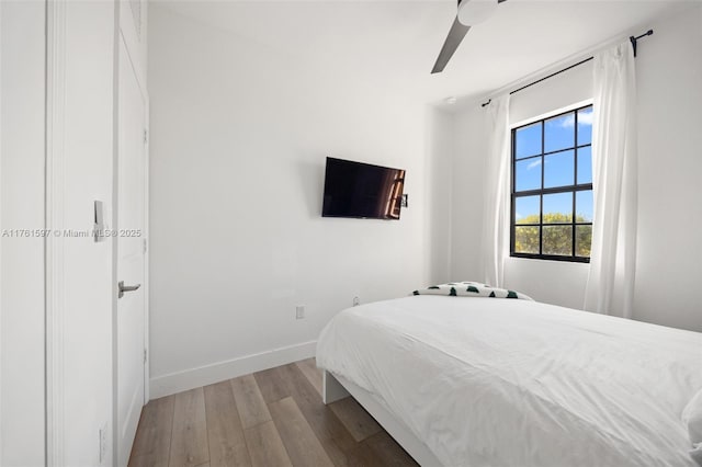 bedroom with baseboards, wood finished floors, and a ceiling fan