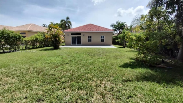 back of house with a yard, a patio area, and stucco siding