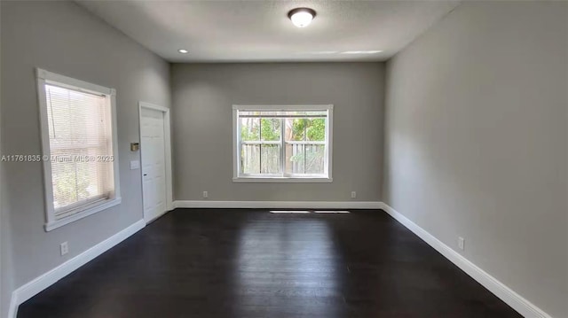 spare room with dark wood-type flooring and baseboards