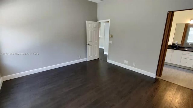 unfurnished bedroom with baseboards and dark wood-style flooring