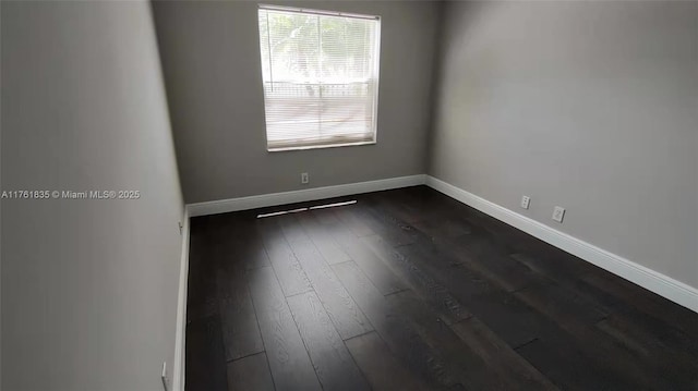 spare room featuring baseboards and dark wood-style flooring