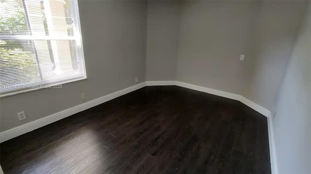 unfurnished room featuring dark wood-type flooring and baseboards