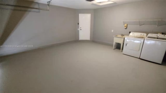 clothes washing area with laundry area, washing machine and dryer, a garage, and a sink