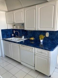 kitchen with dishwasher, light tile patterned flooring, white cabinetry, and a sink