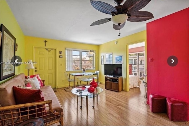 living area featuring baseboards, wood finished floors, and a ceiling fan