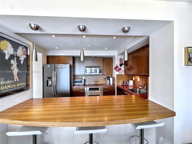 kitchen featuring a sink, stainless steel appliances, a peninsula, and decorative backsplash