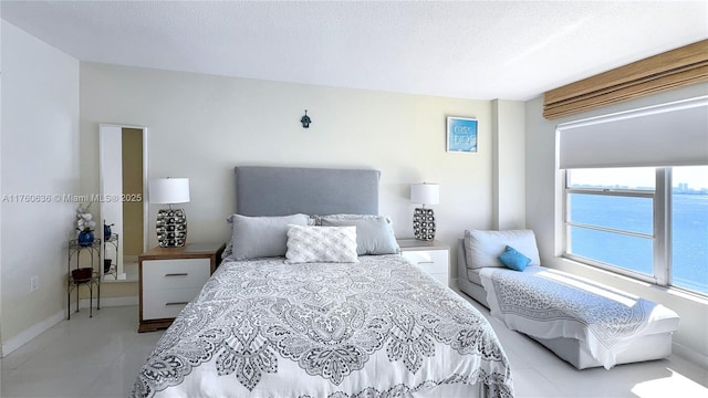 bedroom with tile patterned flooring, baseboards, and a textured ceiling