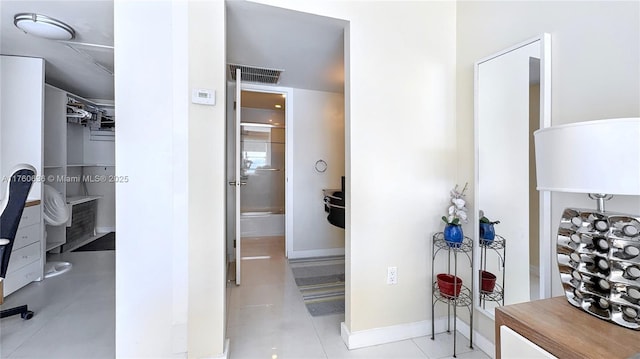 hall with tile patterned floors, baseboards, and visible vents