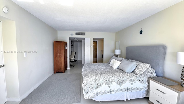 bedroom featuring visible vents, baseboards, light colored carpet, and a textured ceiling